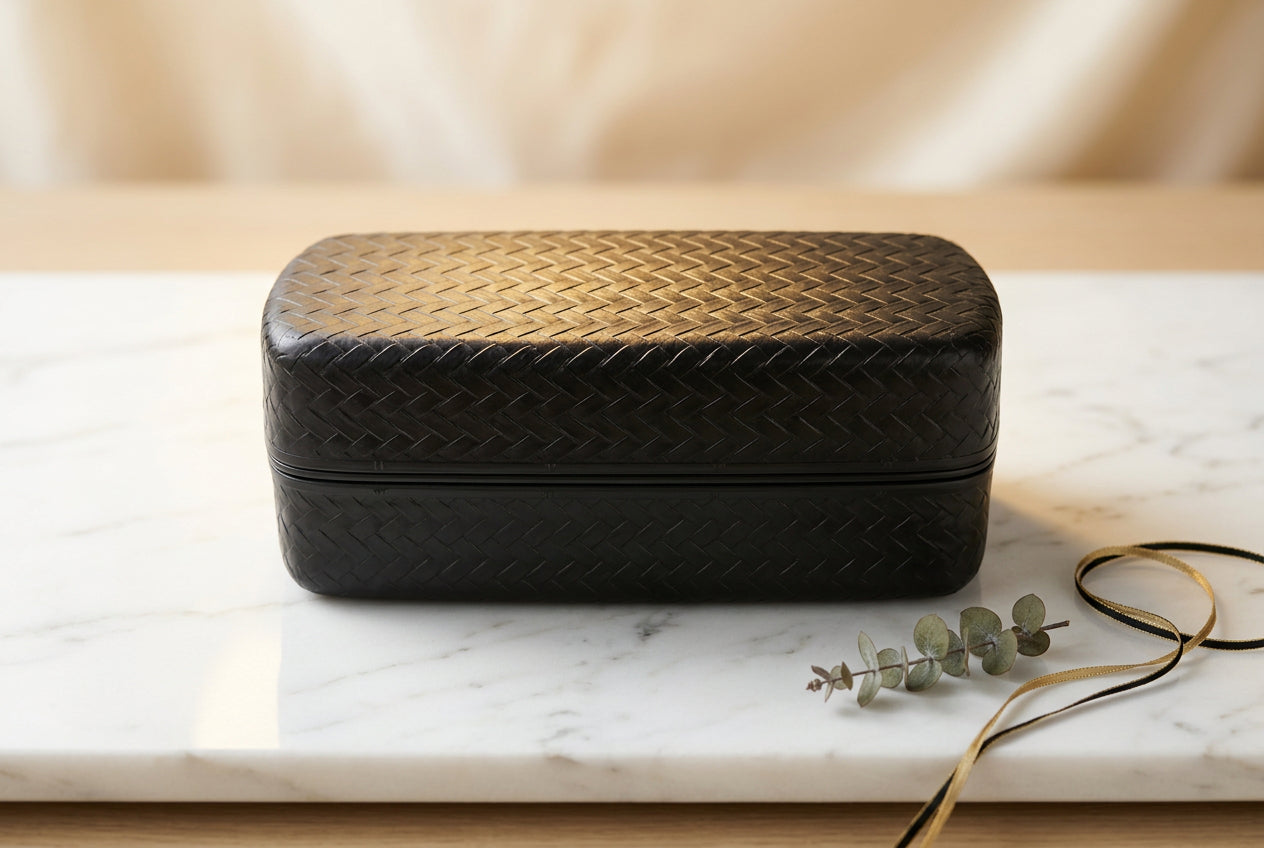 Boîte bento noire fermée avec motif tressé sur le couvercle.