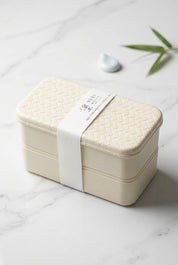 Boîte bento noire à deux niveaux avec couvercle à motif tressé.