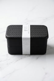 Boîte bento noire Nuri Ajiro à deux niveaux avec bande de présentation.