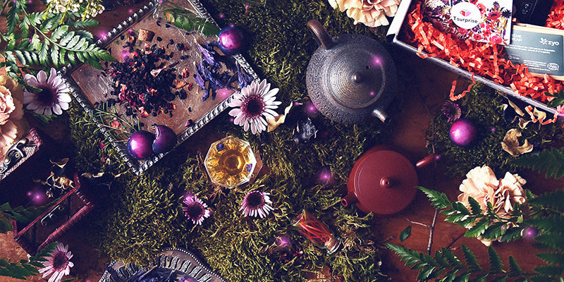 Mise en scène champêtre avec théière, thé en vrac, fleurs sauvages et coffret T•Surprise sur mousse verte, ambiance Saveur bucolique.