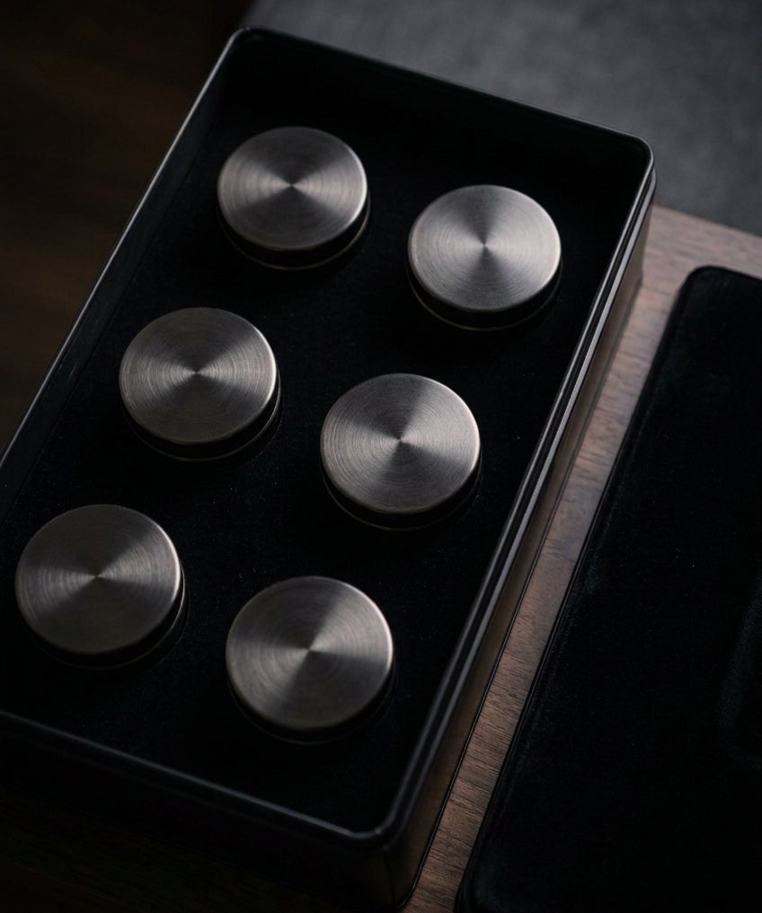Coffret noir ouvert présentant six boîtes rondes dans leur rangement.
